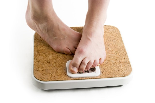a pair of female feet standing on a bathroom scale looking shy about the weight